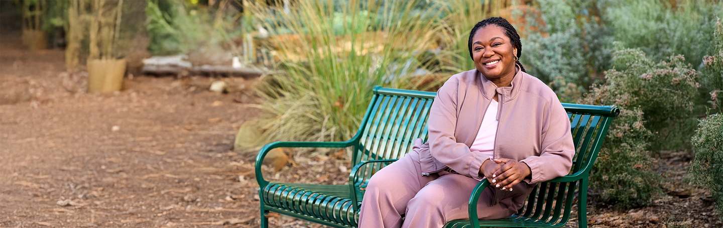Woman seating and smiling on park bench.