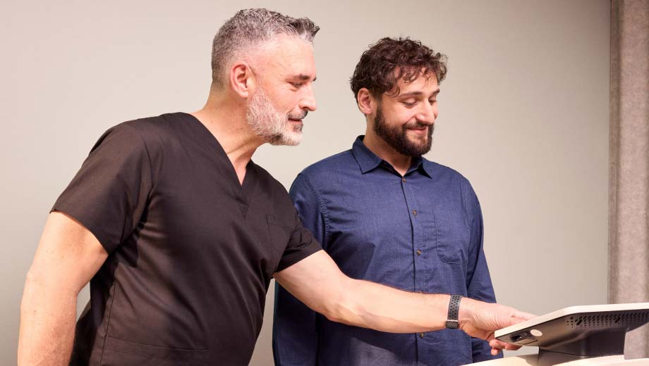 male standing on a scale while a healthcare provider points at the results