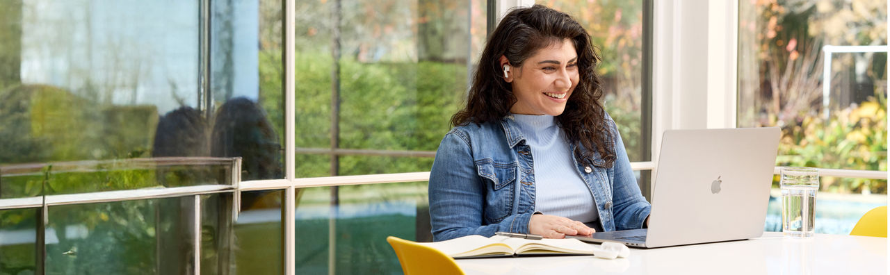 Woman smiling while reading from a laptop.