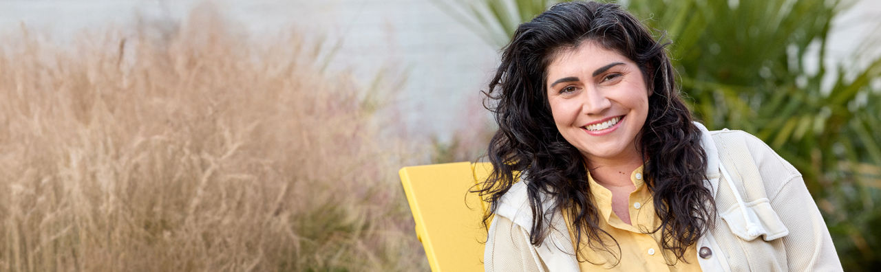 Woman smiling while sitting on yellow chair.  